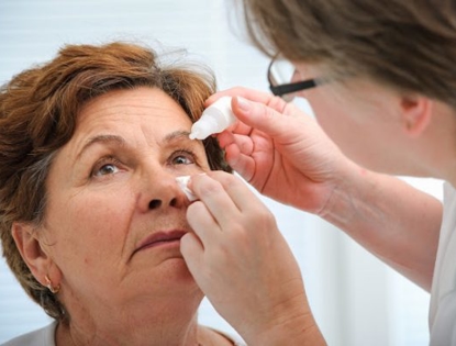 Doctor putting eye drops on woman's eye